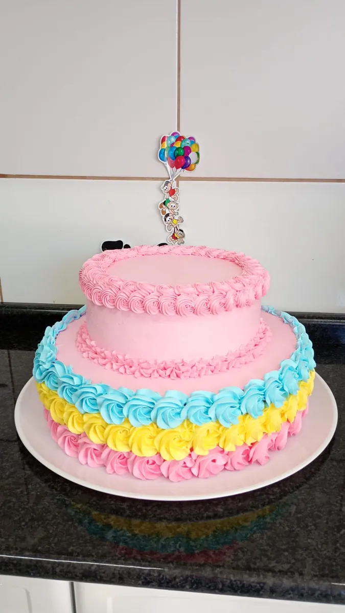 Bolo de dois andares em rosa, azul e amarelo